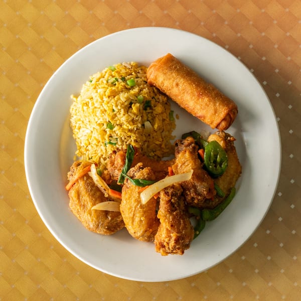 A white plate with fried rice, an egg roll, and fried chicken with vegetables.