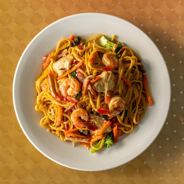 Overhead view of a white plate filled with shrimp and chicken lo mein.