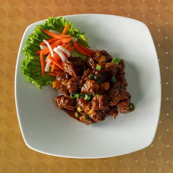 Braised pork ribs with green onions, served with a side of lettuce, carrots, and daikon.