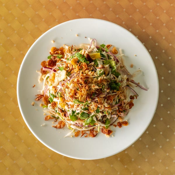 A vibrant chicken salad with shredded cabbage, red onions, herbs, and crispy fried shallots.